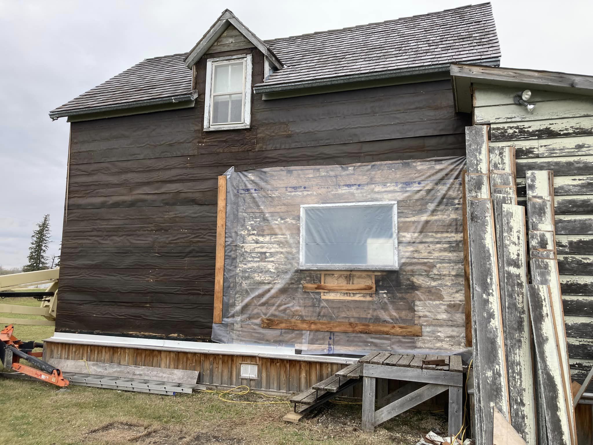 Siding removed, revealing tar paper and logs New Work side of Fagriskogur